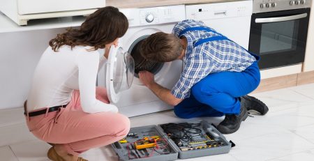 Technician repairing washing machine for homeowner