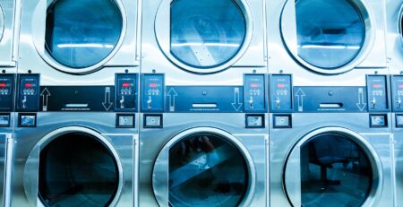 Row of commercial washing machines in laundromat.