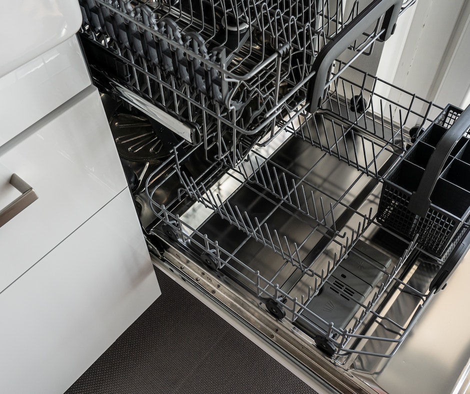 Empty open dishwasher interior with racks.